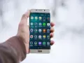 Dłoń trzymająca złoty telefon Samsung z widocznymi ikonami aplikacji.