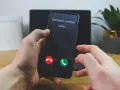 Dłoń trzyma telefon, na ekranie którego widnieje komunikat "Unknown number calling...". Czy odbierze, gdy numer prywatny dzwoni?