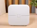 Biały router funbox 7 Orange, z logo operatora, stoi na drewnianym biurku obok książek i rośliny.
