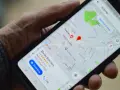 Dłoń trzyma smartfon z mapą Google. Widoczne są google maps współrzędne i wyszukiwanie "butcher".
