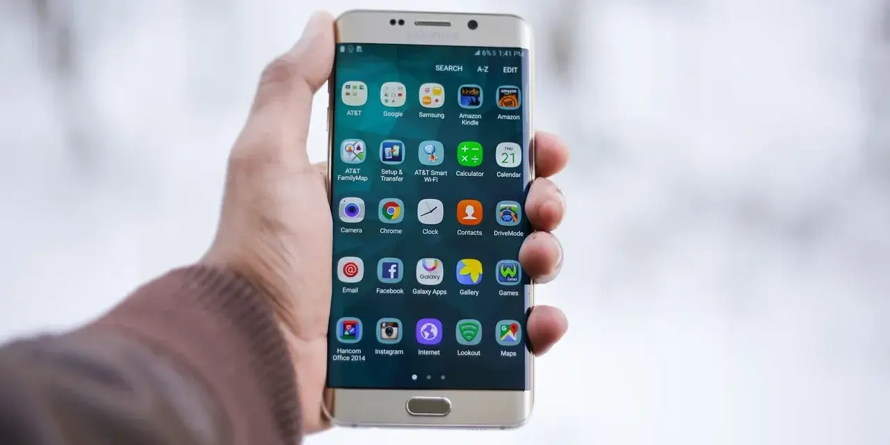 Dłoń trzymająca złoty telefon Samsung z widocznymi ikonami aplikacji.