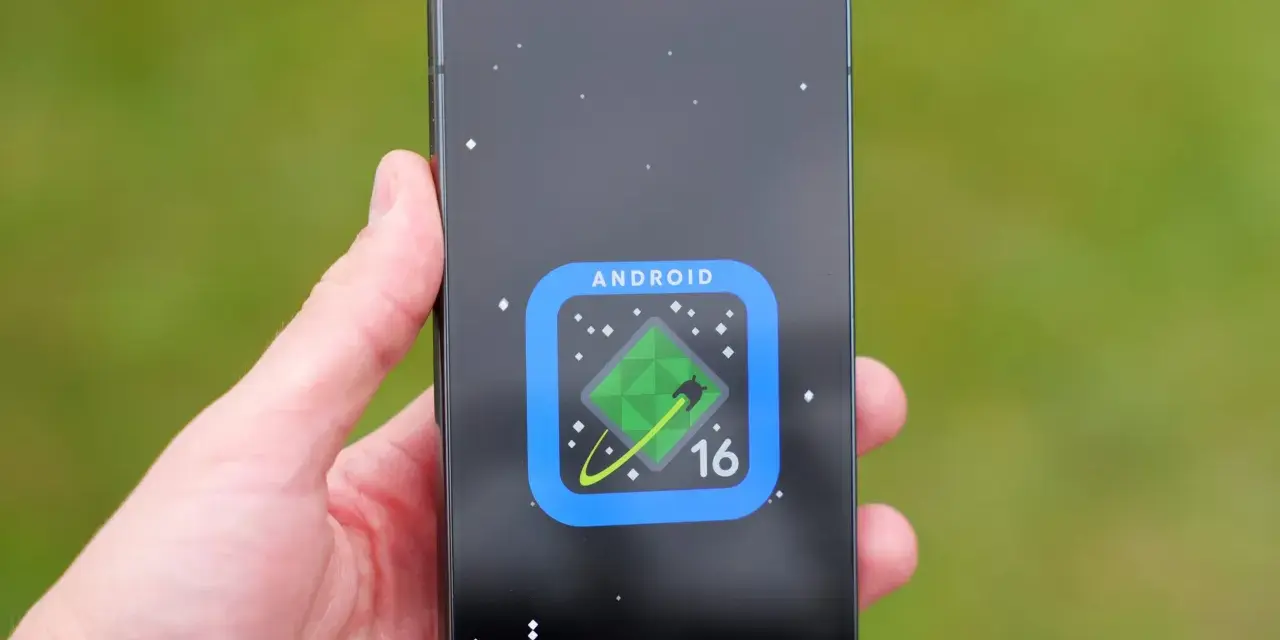Dłoń trzyma smartfon z ikoną Android 16 na ekranie, przypominającą zielony kryształ na tle kosmosu.