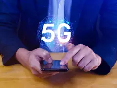 Dłoń na smartfonie, symbol 5G nad nim. Dowiedz się, jak wyłączyć 5G w telefonie, aby kontrolować połączenie.