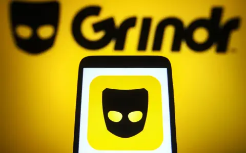Ikona aplikacji Grindr na ekranie telefonu, na tle logo Grindr.