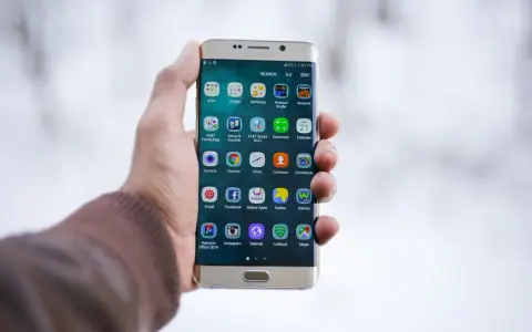 Dłoń trzymająca złoty telefon Samsung z widocznymi ikonami aplikacji.