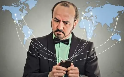 Mężczyzna w garniturze z telefonem, zastanawia się, co to roaming. Mapa świata z połączeniami sugeruje globalną sieć.