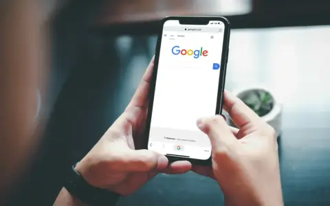 Ręce trzymają telefon z otwartą wyszukiwarką Google. Szukasz informacji, jak usunąć konto Google z telefonu?