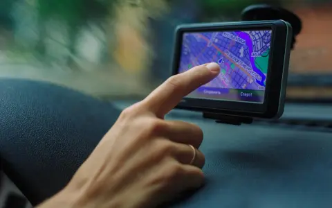 Palec dotyka ekranu nawigacji, uruchamiając mydrive connect. Widok z samochodu na mapę.