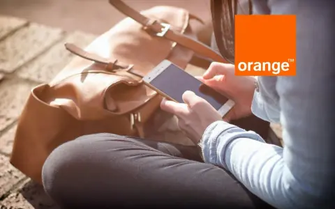 Kobieta z telefonem w dłoni, obok brązowa torba. Idealny dzień na środy z Orange.