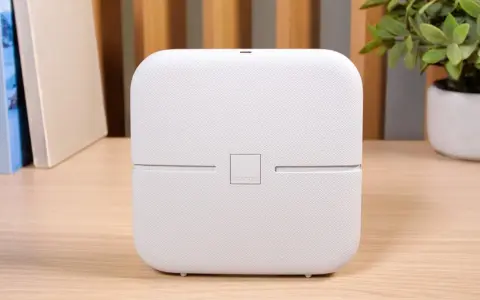 Biały router funbox 7 Orange, z logo operatora, stoi na drewnianym biurku obok książek i rośliny.