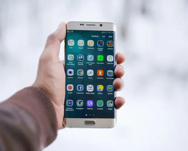Dłoń trzymająca złoty telefon Samsung z widocznymi ikonami aplikacji.