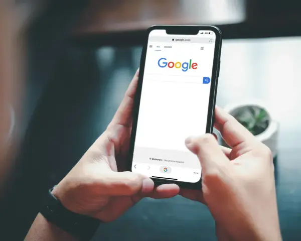 Ręce trzymają telefon z otwartą wyszukiwarką Google. Szukasz informacji, jak usunąć konto Google z telefonu?