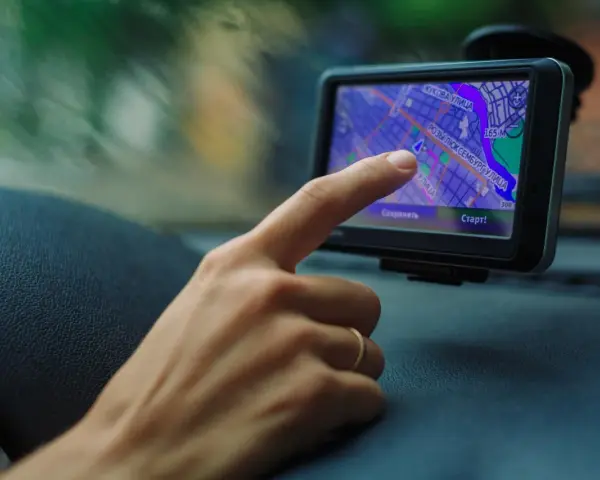 Palec dotyka ekranu nawigacji, uruchamiając mydrive connect. Widok z samochodu na mapę.