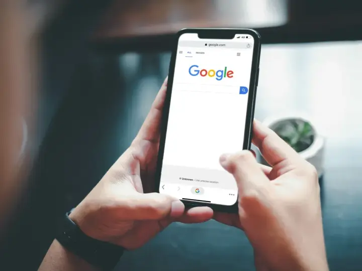 Ręce trzymają telefon z otwartą wyszukiwarką Google. Szukasz informacji, jak usunąć konto Google z telefonu?