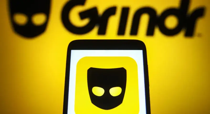 Ikona aplikacji Grindr na ekranie telefonu, na tle logo Grindr.
