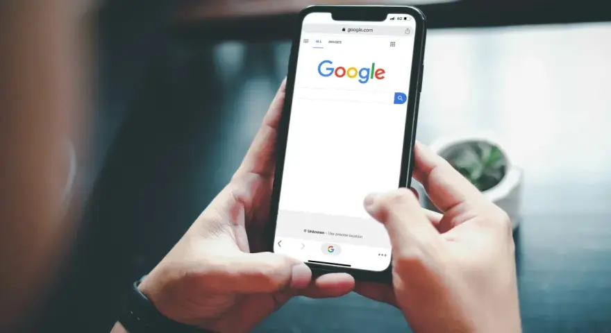 Ręce trzymają telefon z otwartą wyszukiwarką Google. Szukasz informacji, jak usunąć konto Google z telefonu?