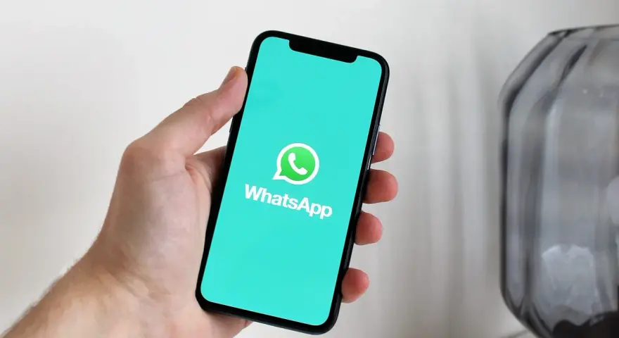 Dłoń trzyma smartfon z logo WhatsApp. Idealne narzędzie do komunikacji, gdy masz internet za granicą.