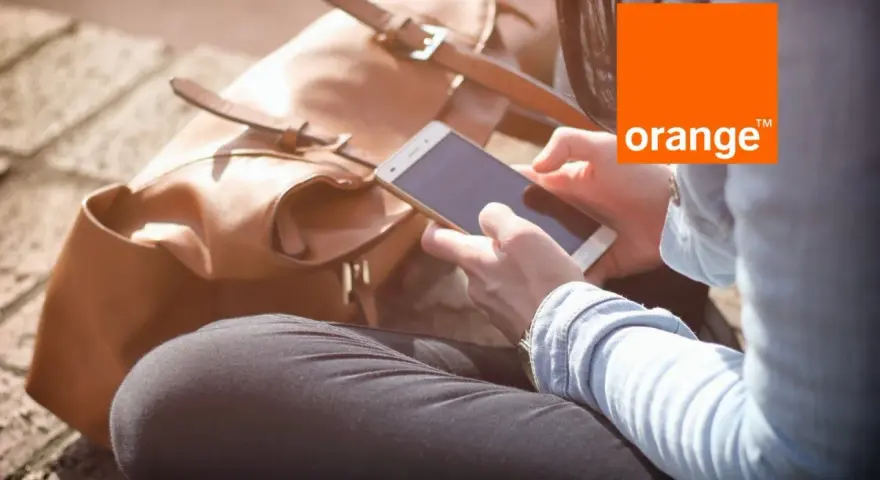 Kobieta z telefonem w dłoni, obok brązowa torba. Idealny dzień na środy z Orange.
