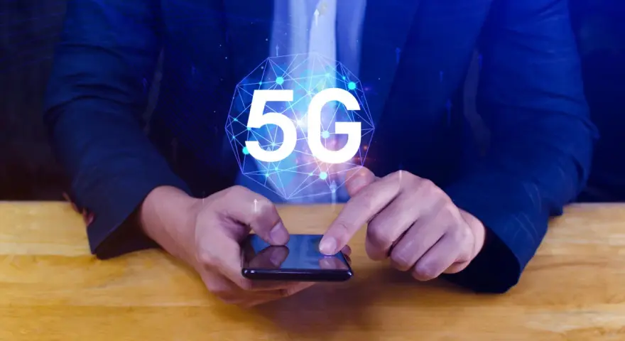 Dłoń na smartfonie, symbol 5G nad nim. Dowiedz się, jak wyłączyć 5G w telefonie, aby kontrolować połączenie.