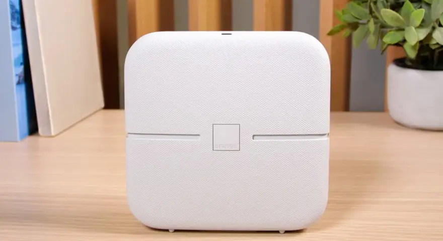 Biały router funbox 7 Orange, z logo operatora, stoi na drewnianym biurku obok książek i rośliny.
