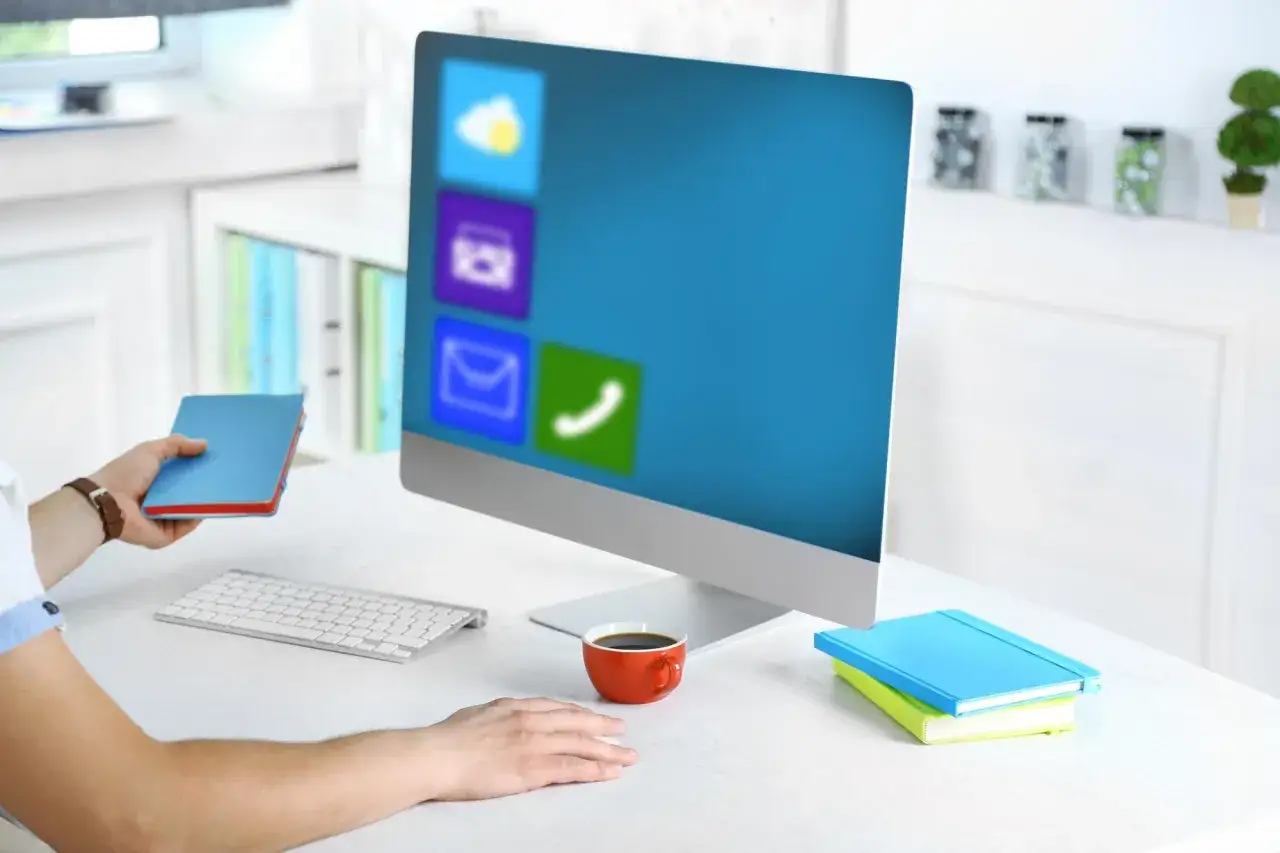 Pracownik biurowy korzysta z komputera z ikonami aplikacji, w tym z pakietu WPS Office, podczas przerwy na kawę.