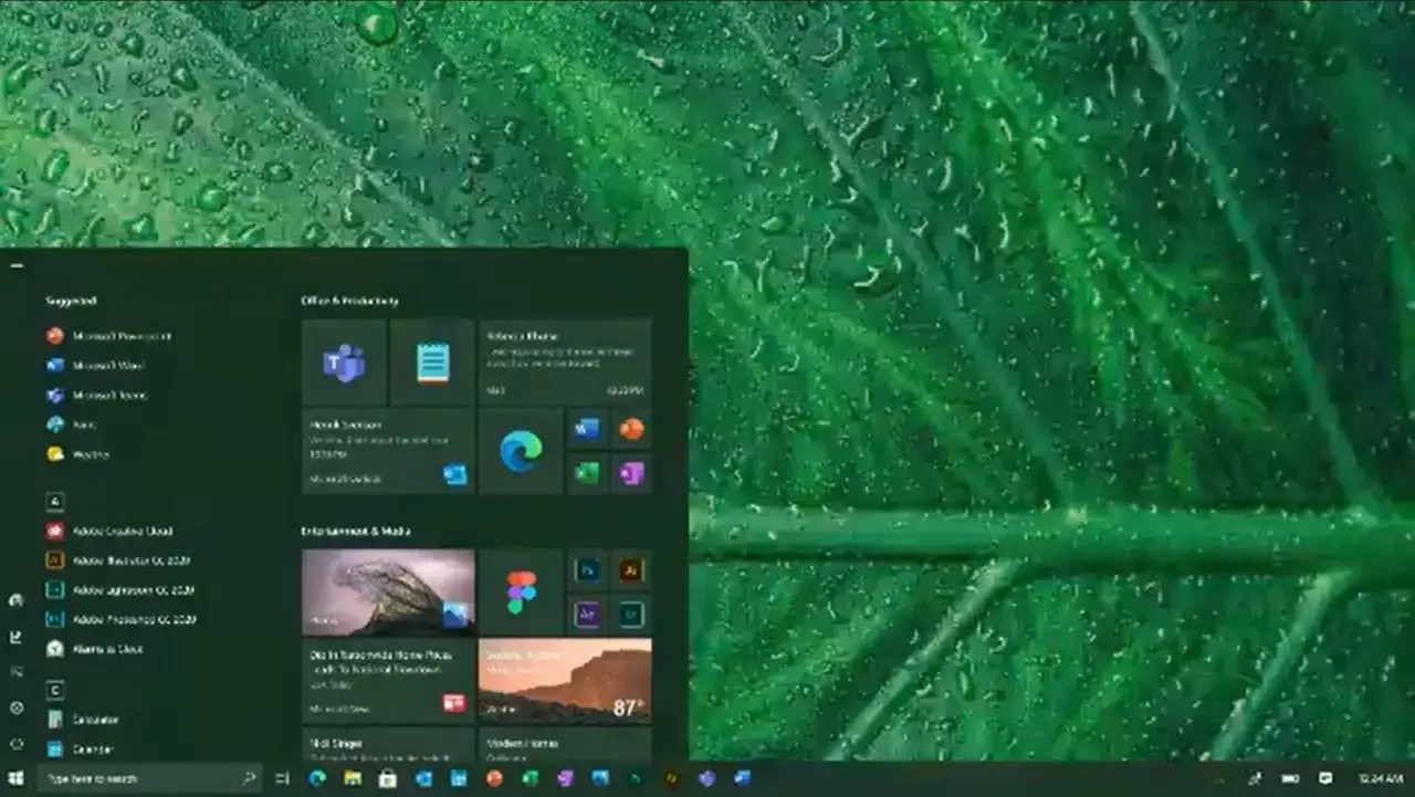 Menu Start systemu Windows 10 na tle zielonych liści z kroplami deszczu.