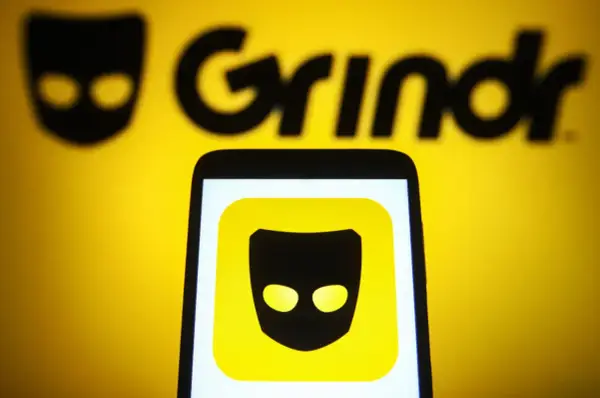 Ikona aplikacji Grindr na ekranie telefonu, na tle logo Grindr.