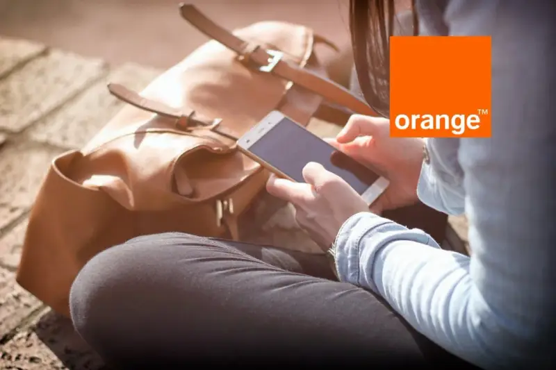 Kobieta z telefonem w dłoni, obok brązowa torba. Idealny dzień na środy z Orange.