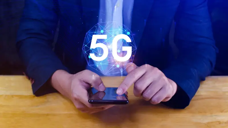 Dłoń na smartfonie, symbol 5G nad nim. Dowiedz się, jak wyłączyć 5G w telefonie, aby kontrolować połączenie.